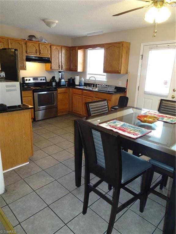 kitchen featuring fridge, tile patterned floors, stainless steel electric range oven, and sink