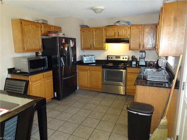 kitchen with stainless steel appliances, sink, light tile patterned floors, and a textured ceiling