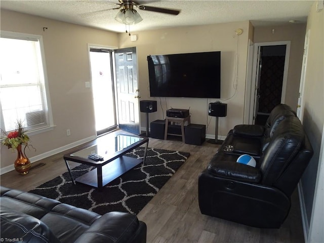 living room featuring dark wood-type flooring, ceiling fan, and a textured ceiling