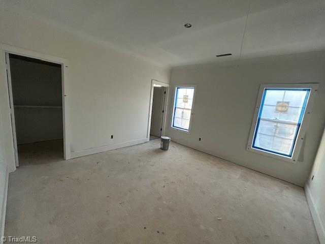 unfurnished bedroom featuring a walk in closet, concrete floors, and visible vents