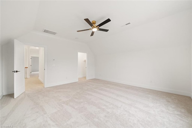 spare room featuring visible vents, light colored carpet, a ceiling fan, and lofted ceiling