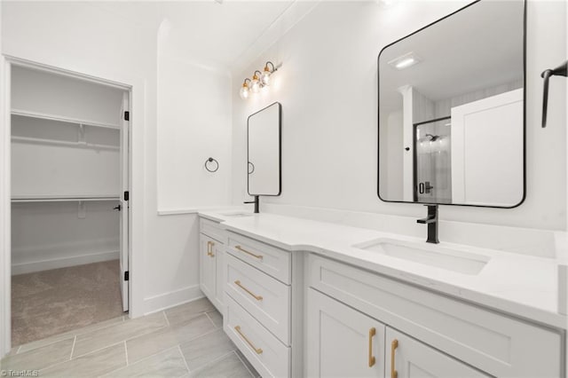 full bathroom with double vanity, a stall shower, a walk in closet, and a sink