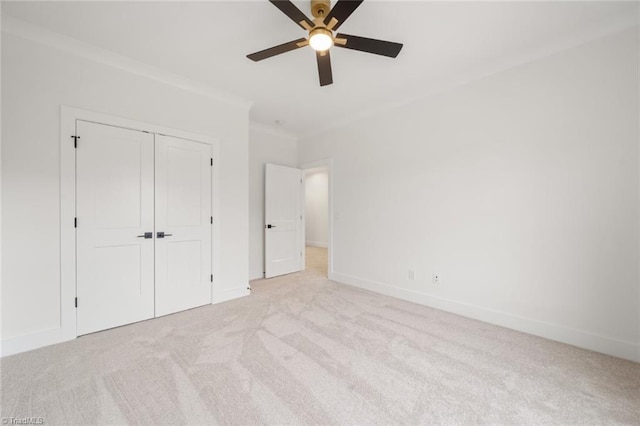 unfurnished bedroom with ceiling fan, baseboards, ornamental molding, carpet flooring, and a closet