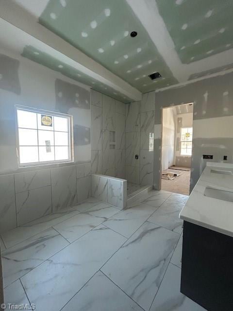 full bath featuring marble finish floor, a healthy amount of sunlight, and double vanity