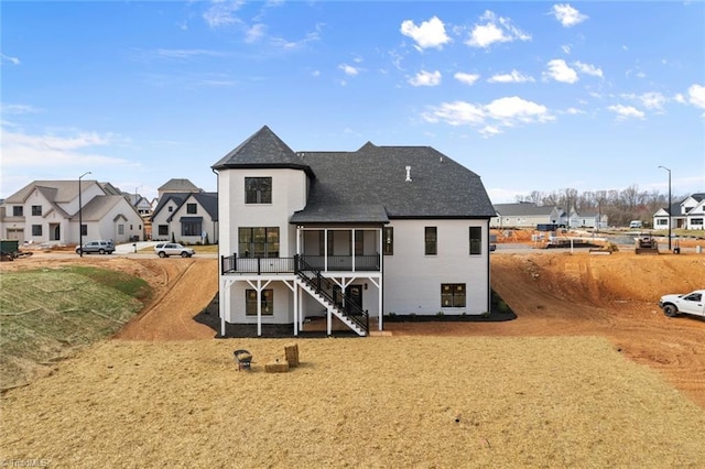 back of property with a residential view, stairway, and a sunroom