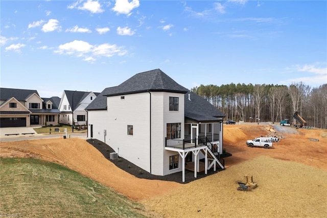 rear view of house featuring roof with shingles