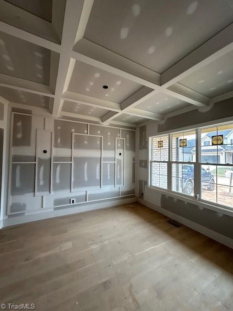 spare room featuring beamed ceiling, light wood-style floors, visible vents, and coffered ceiling