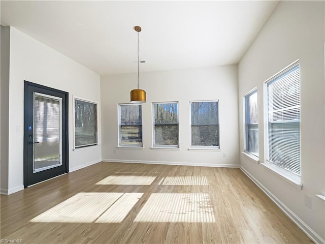 unfurnished dining area with baseboards and wood finished floors