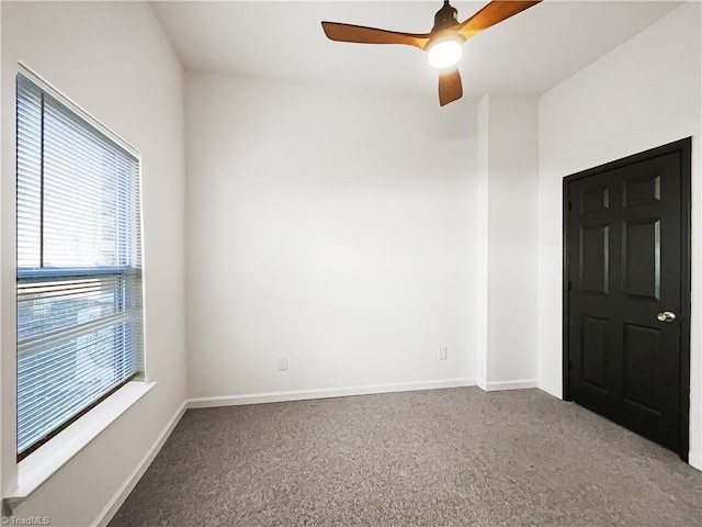 carpeted spare room featuring ceiling fan and baseboards