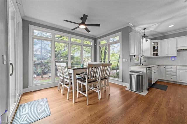interior space featuring wood finished floors, visible vents, ornamental molding, and ceiling fan