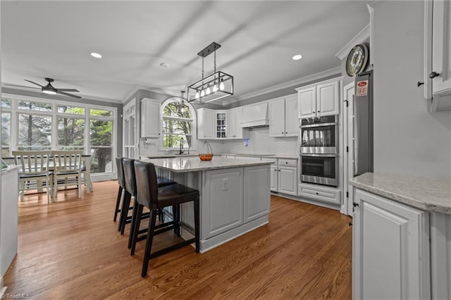 kitchen with ornamental molding, a center island, white cabinetry, ceiling fan, and stainless steel appliances