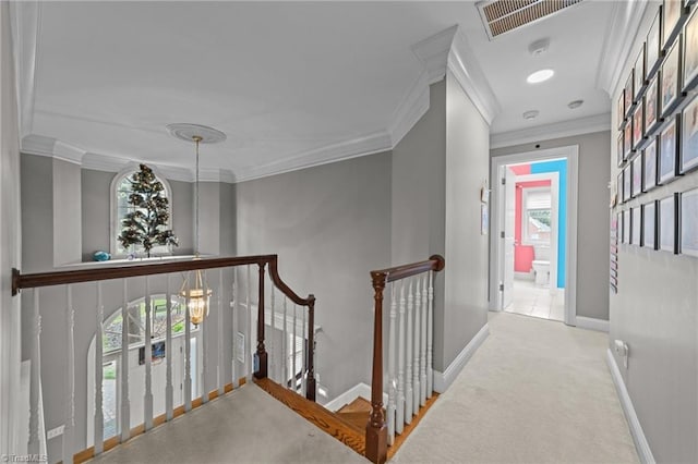 corridor featuring baseboards, ornamental molding, carpet flooring, an upstairs landing, and visible vents
