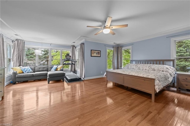 bedroom featuring crown molding, baseboards, light wood finished floors, and a ceiling fan
