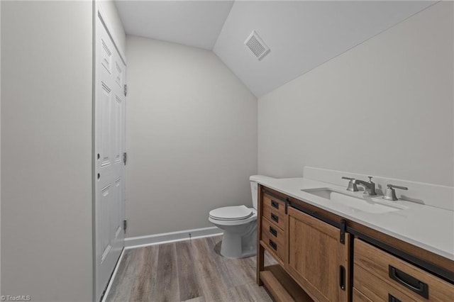 bathroom with vanity, toilet, visible vents, lofted ceiling, and wood finished floors