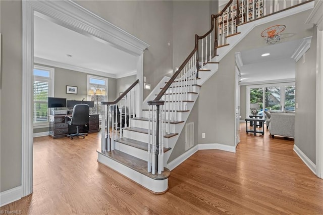 stairs featuring baseboards, wood finished floors, and a healthy amount of sunlight