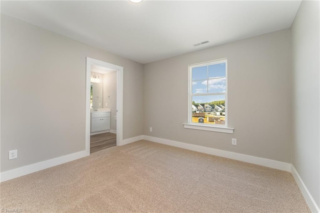 unfurnished bedroom featuring ensuite bath and carpet flooring