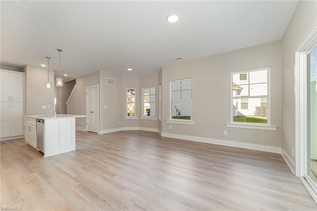 unfurnished living room featuring sink and light hardwood / wood-style floors