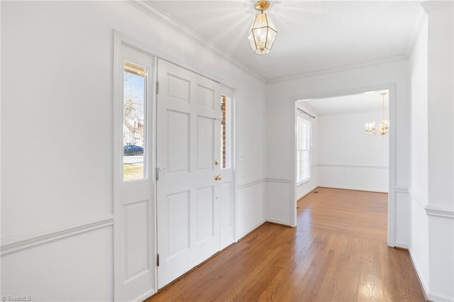 entryway with ornamental molding, a chandelier, and hardwood / wood-style flooring