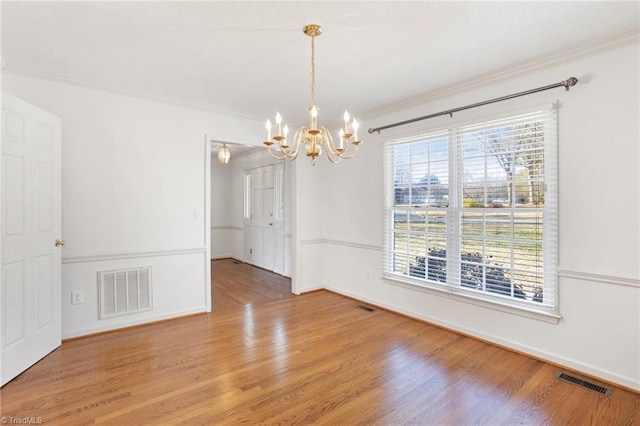 spare room with hardwood / wood-style flooring, an inviting chandelier, and ornamental molding