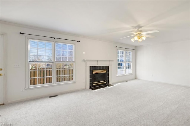 unfurnished living room with a tile fireplace, ceiling fan, crown molding, and light carpet