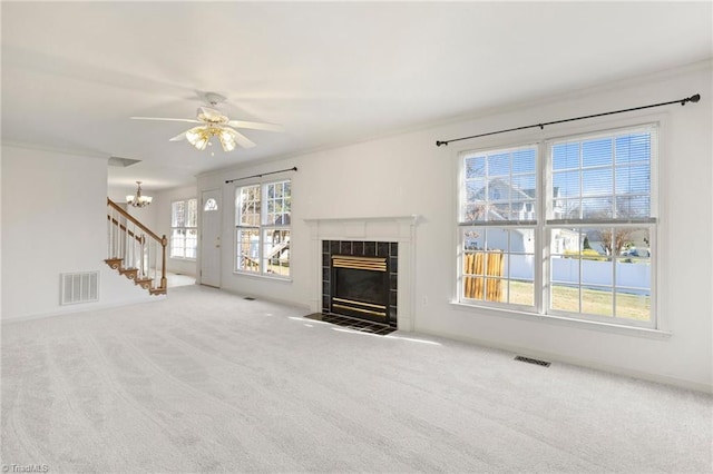 living room featuring ceiling fan with notable chandelier, plenty of natural light, carpet floors, and a tiled fireplace