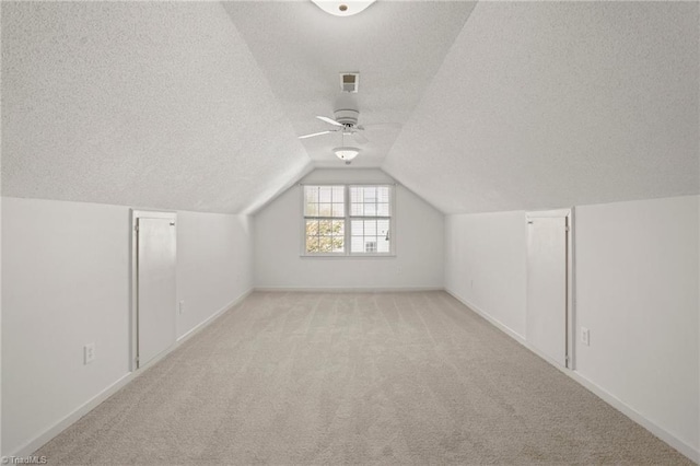 additional living space featuring a textured ceiling, ceiling fan, light colored carpet, and vaulted ceiling