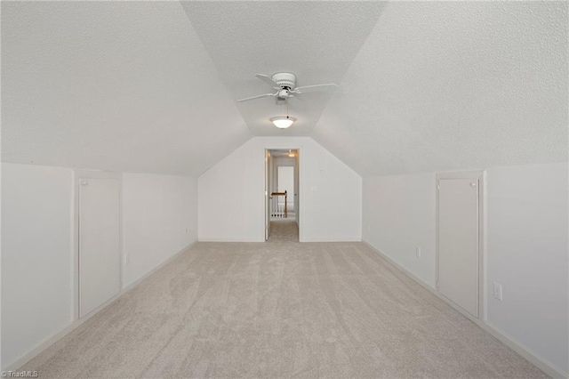 additional living space featuring ceiling fan, lofted ceiling, a textured ceiling, and light carpet