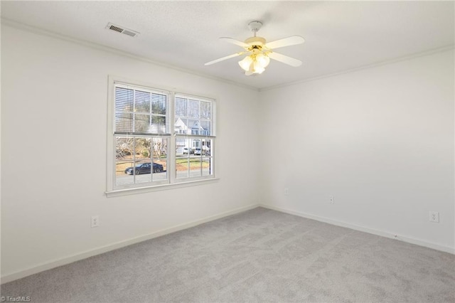 carpeted spare room with ceiling fan and ornamental molding