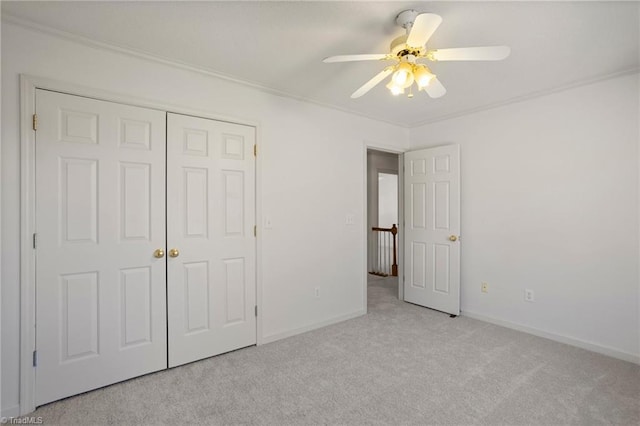 unfurnished bedroom with a closet, crown molding, ceiling fan, and light colored carpet