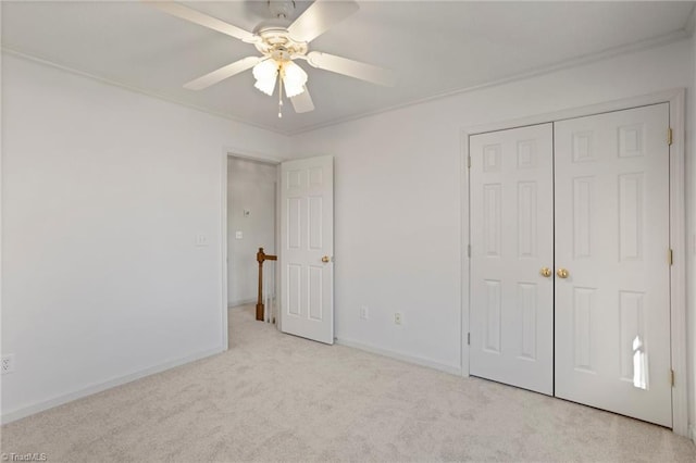 unfurnished bedroom featuring ceiling fan, a closet, light carpet, and ornamental molding