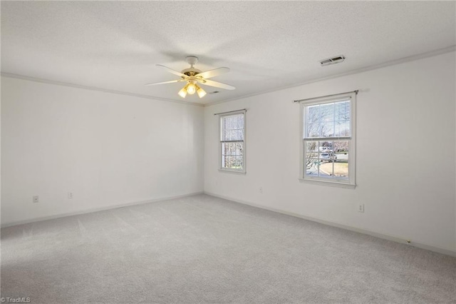 carpeted spare room with crown molding, ceiling fan, and a textured ceiling