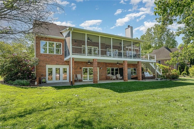 rear view of property featuring a ceiling fan, a sunroom, a patio area, a chimney, and a yard