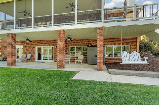 back of property with a ceiling fan, a balcony, a yard, and a patio area