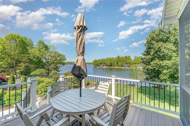 wooden terrace featuring a water view, outdoor dining area, and a lawn