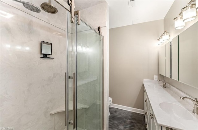 full bath with a stall shower, double vanity, toilet, and baseboards