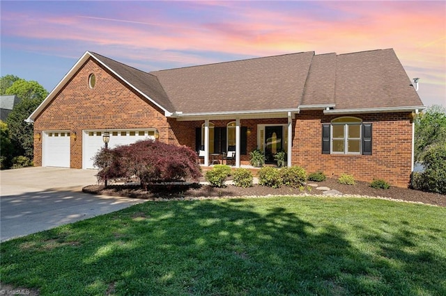 view of front facade with covered porch, brick siding, a front yard, concrete driveway, and a garage