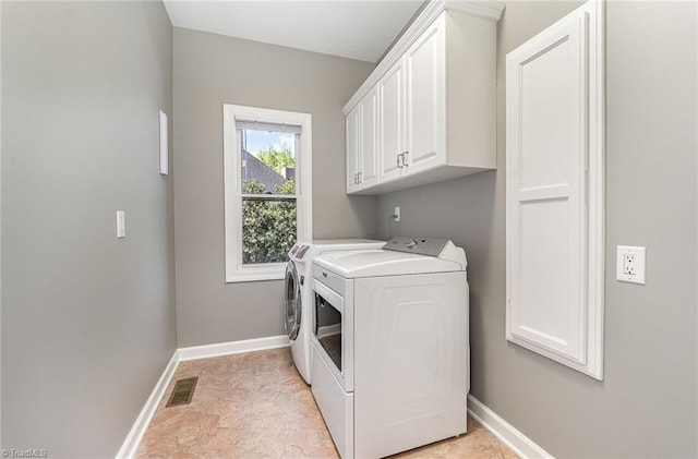 laundry room with washing machine and dryer, cabinet space, and baseboards