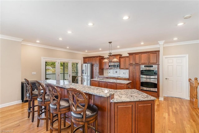 kitchen with a spacious island, stainless steel appliances, brown cabinets, light wood-style floors, and recessed lighting