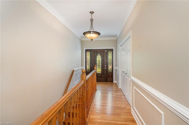 corridor featuring ornamental molding, light wood-style flooring, and an upstairs landing
