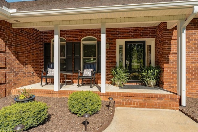 property entrance featuring a porch and brick siding