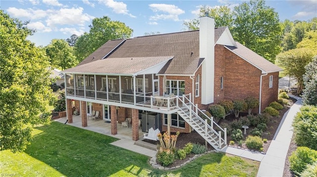 rear view of house featuring a sunroom, a patio, brick siding, and a chimney