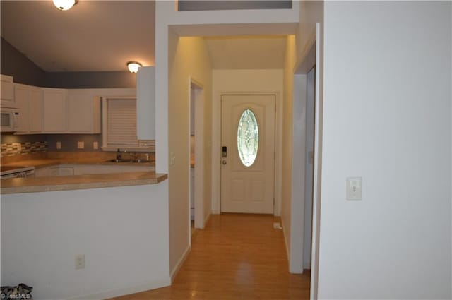 kitchen with white cabinetry, light wood-type flooring, range, and sink