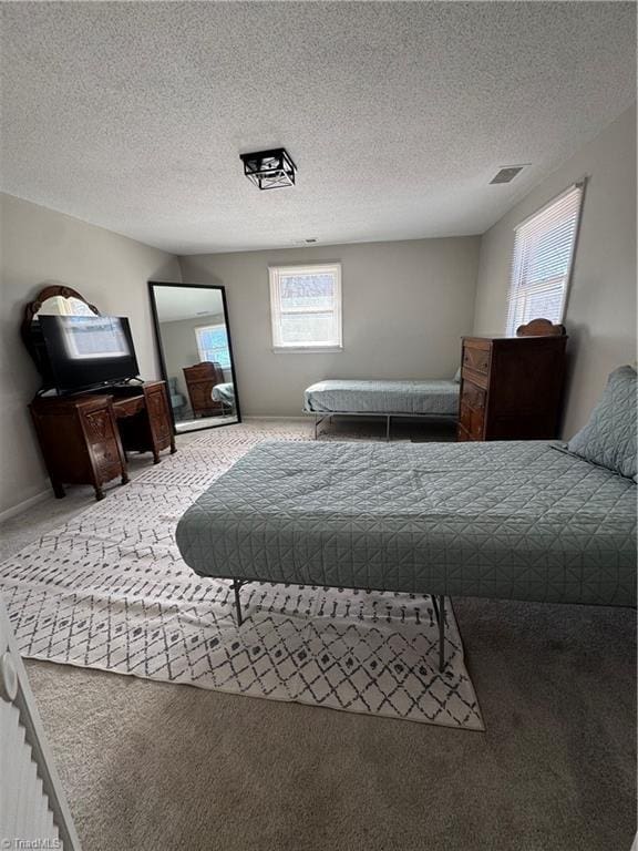 bedroom with baseboards, carpet flooring, visible vents, and a textured ceiling