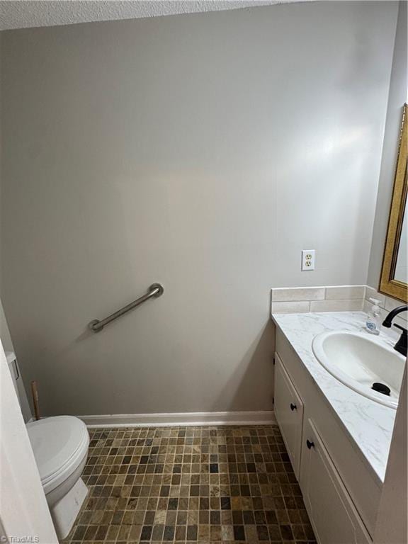 bathroom with vanity, toilet, and baseboards