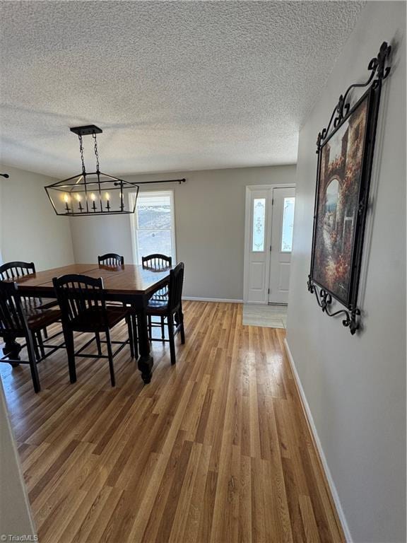 dining space featuring a textured ceiling, a barn door, wood finished floors, and baseboards