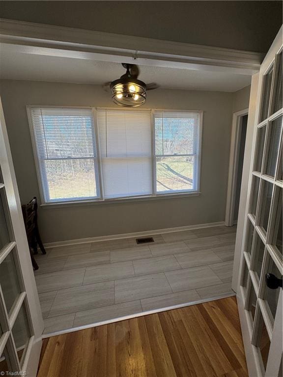 unfurnished dining area featuring a healthy amount of sunlight, visible vents, baseboards, and light wood finished floors