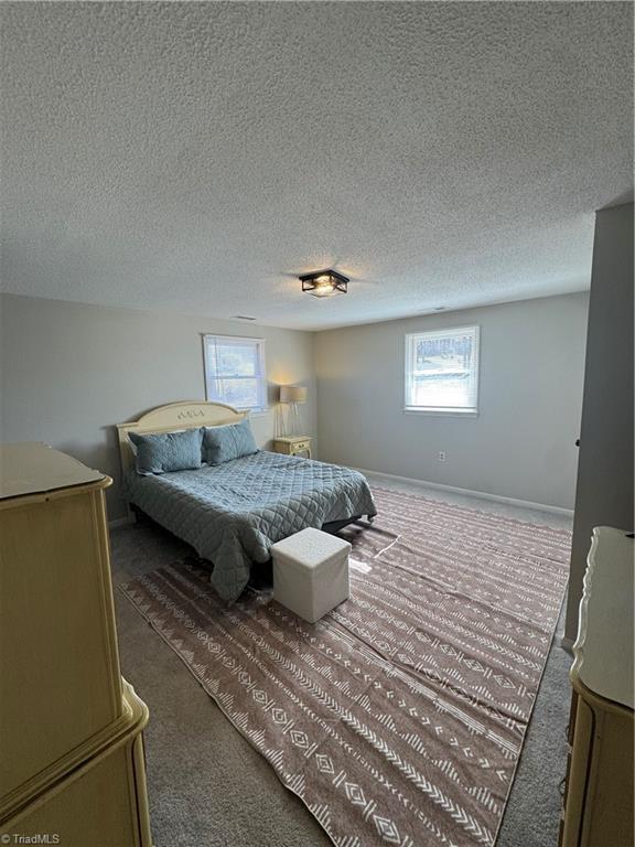 bedroom with dark carpet, a textured ceiling, and baseboards