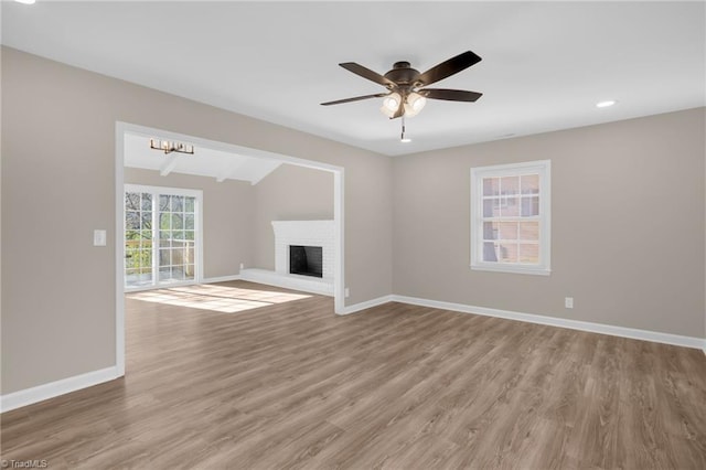 unfurnished living room featuring ceiling fan, a fireplace, hardwood / wood-style floors, and vaulted ceiling