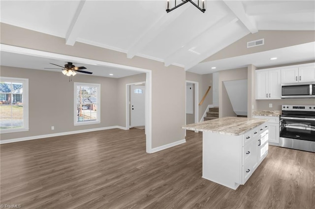 kitchen with appliances with stainless steel finishes, lofted ceiling with beams, white cabinets, dark hardwood / wood-style floors, and a kitchen island