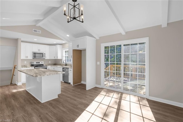 kitchen featuring an inviting chandelier, white cabinets, pendant lighting, a kitchen island, and appliances with stainless steel finishes